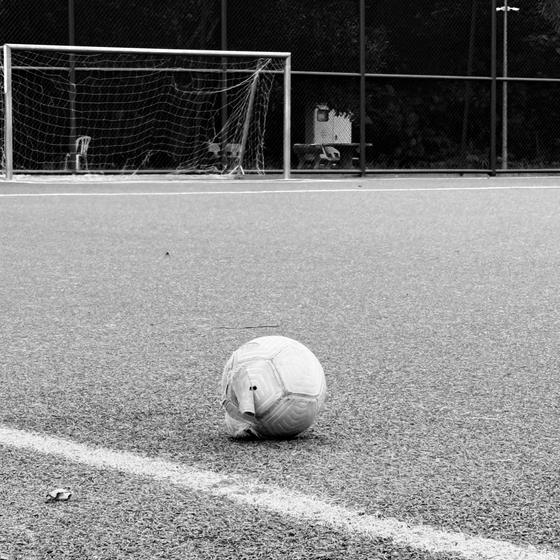 Black and white empty football pitch with a ball